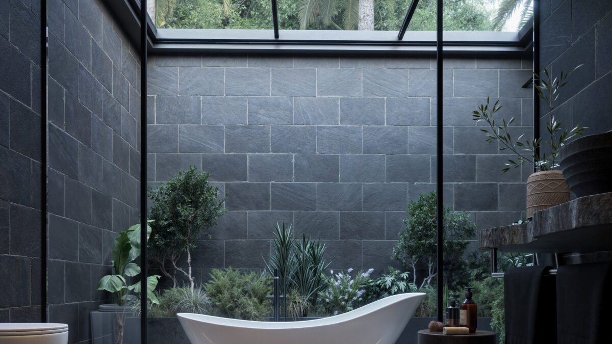 Modern open-air bathroom with dark stone walls and skylight